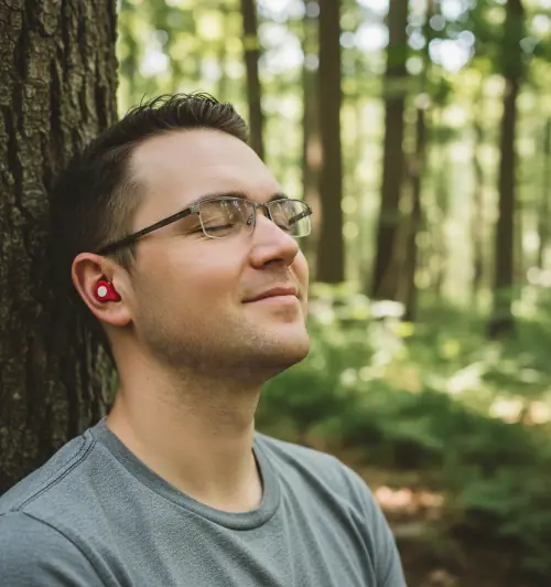 Marcus in the forest with red Orphit earbuds in his ears